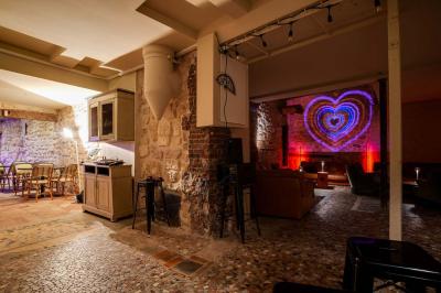 Miniature Location salle Nanterre (Hauts-de-Seine) - Les Enfants Terribles #11 Façade d'un café-restaurant avec terrasse vide, éclairée par des lumières colorées en soirée pluvieuse.