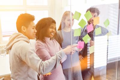 Personnes pratiquant le yoga sur une plage au coucher du soleil, en position debout avec les bras levés.