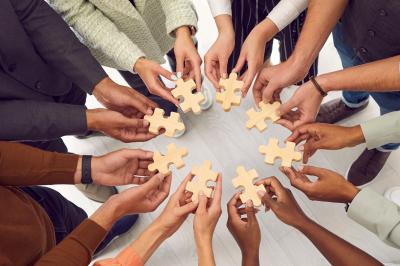 Personnes pratiquant le yoga sur une plage au coucher du soleil, en position debout avec les bras levés.