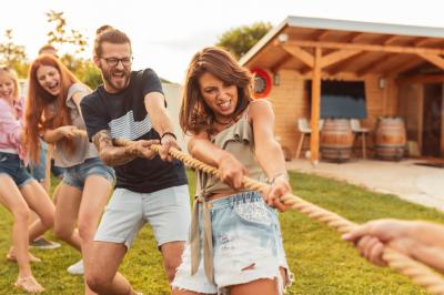 Personnes pratiquant le yoga sur une plage au coucher du soleil, en position debout avec les bras levés.