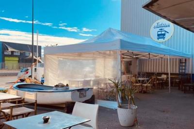 Miniature Location salle Sète (Hérault) - Le Truck de la Conserverie #4 Des personnes assises à des tables sous une pergola ombragée, discutant et partageant un moment convivial.