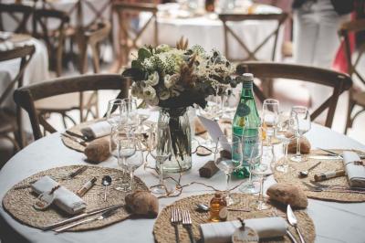 Salle décorée avec des fûts recyclés en tables, éclairage chaleureux et éléments rustiques en bois.