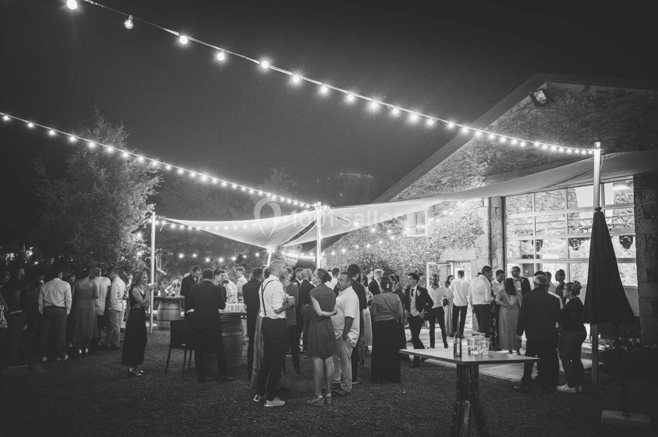 Groupe de personnes rassemblées en soirée sous des guirlandes lumineuses dans une cour extérieure.