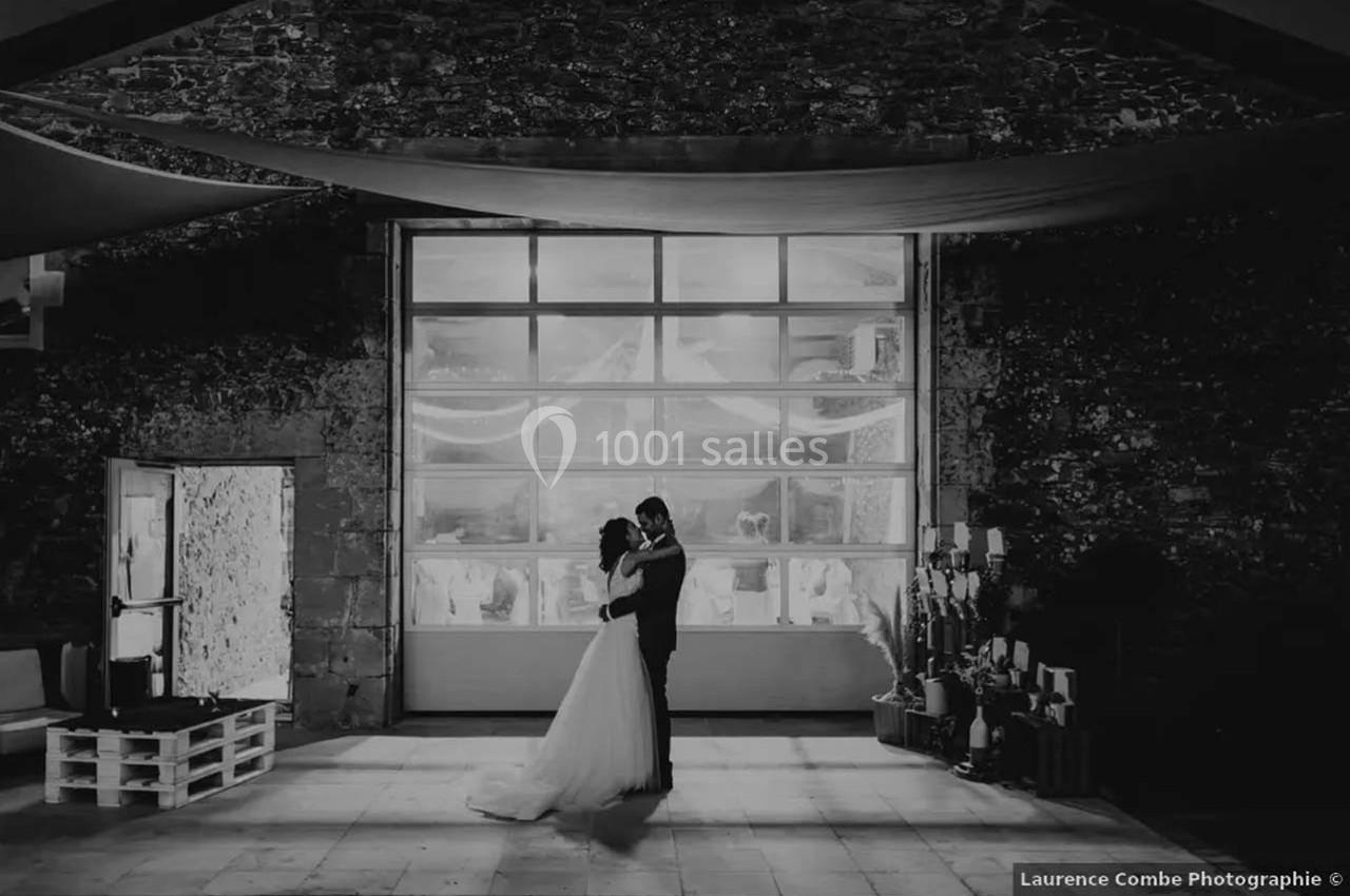 Un couple danse dans une salle en pierre éclairée par une grande baie vitrée en arrière-plan.