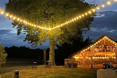 Salle décorée avec des fûts recyclés en tables, éclairage chaleureux et éléments rustiques en bois.