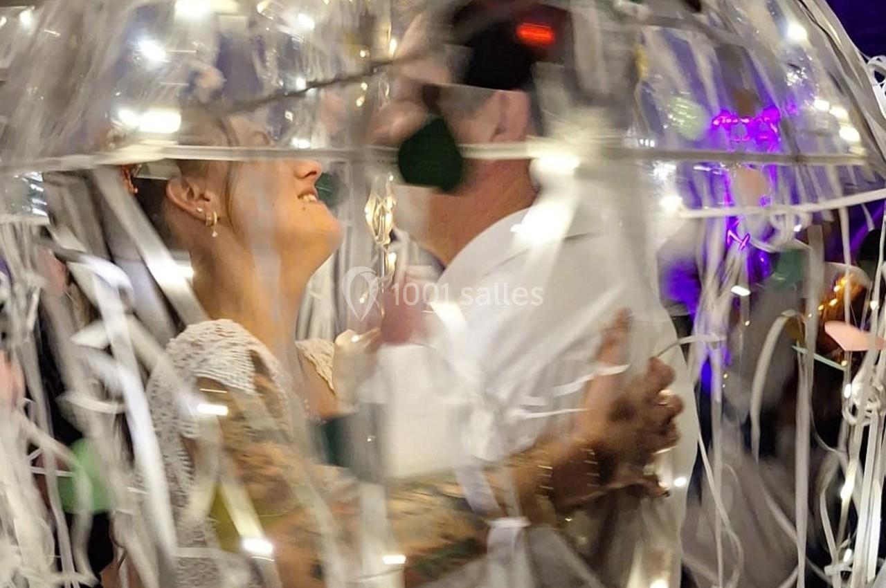 Un couple danse sous des lumières et des décorations festives, entouré de rubans et d'une ambiance lumineuse.