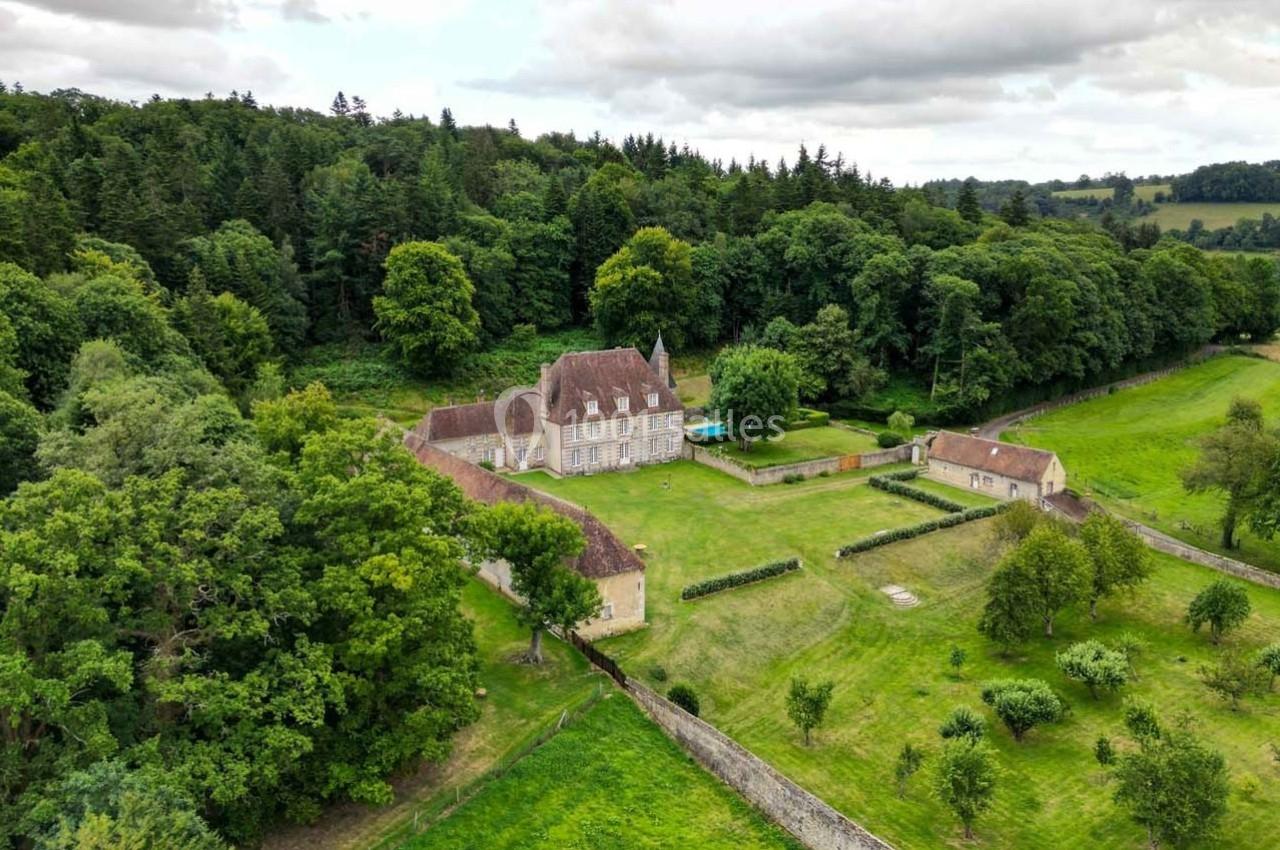 Vue aérienne d'un domaine avec un manoir entouré de jardins, de murs en pierre et de forêts verdoyantes.