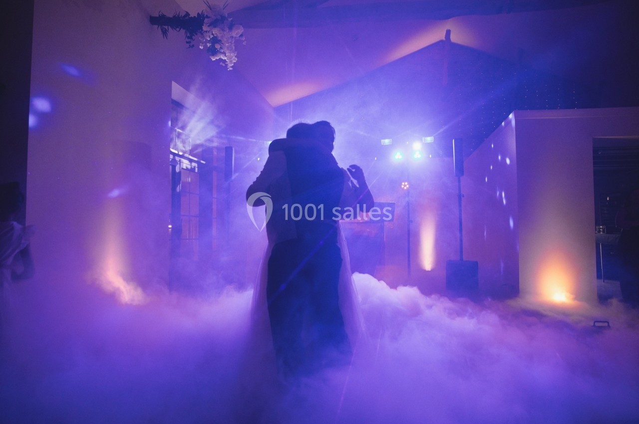 Un couple danse dans une ambiance tamisée avec des lumières colorées et de la fumée au sol.