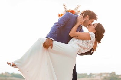 Deux mains tendues l'une vers l'autre au-dessus d'un champ de tournesols fanés.
