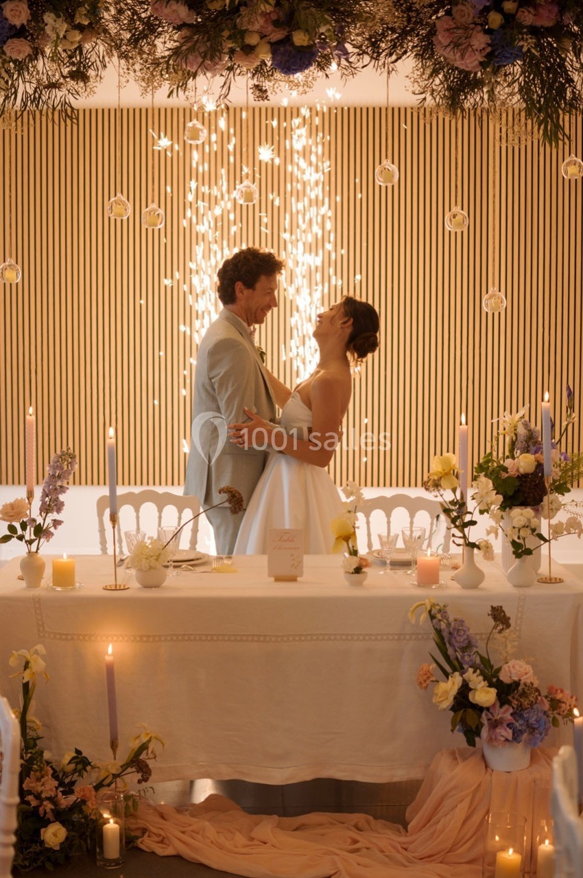 Un couple dansant devant une table décorée de fleurs, avec des étincelles en arrière-plan.