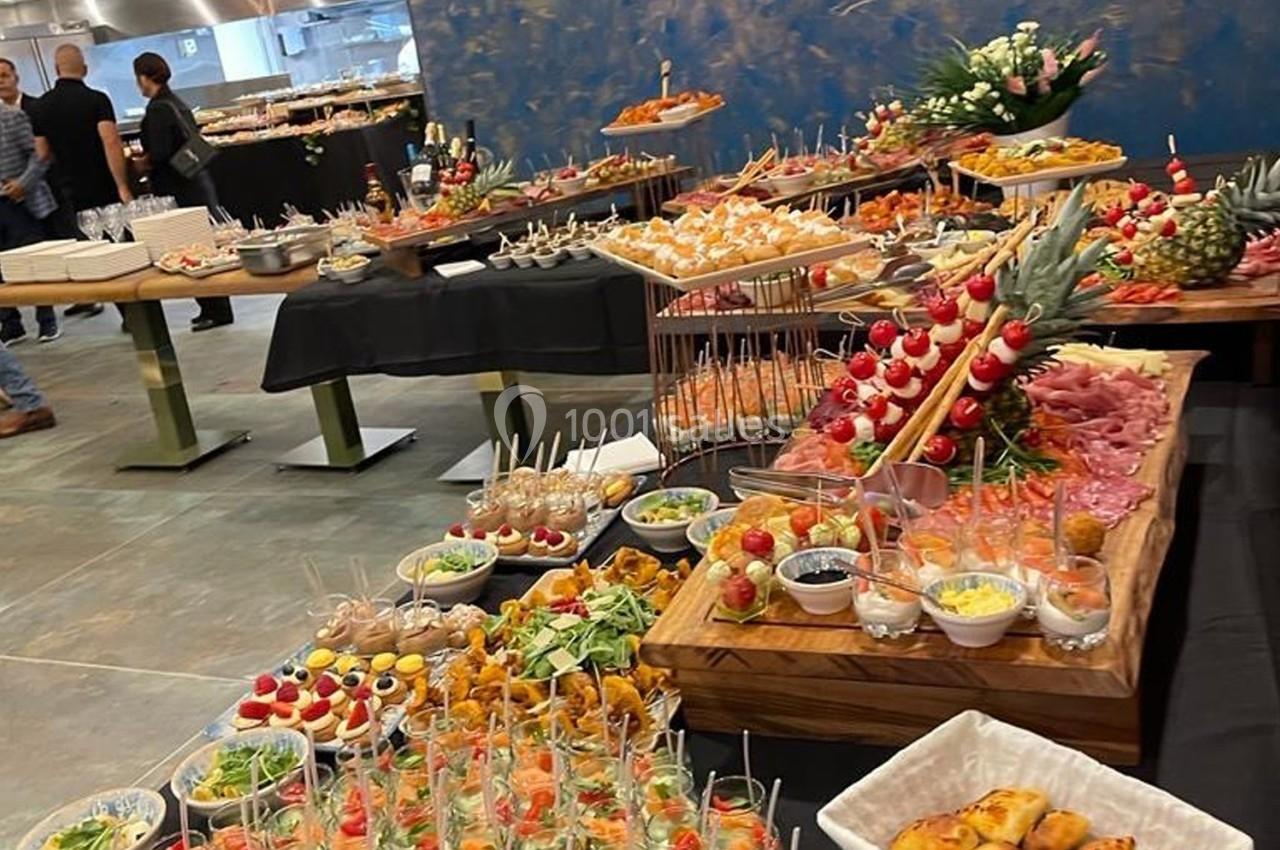 Buffet varié avec des plats colorés, incluant brochettes, verrines, charcuteries et desserts, disposés sur plusieurs tables.
