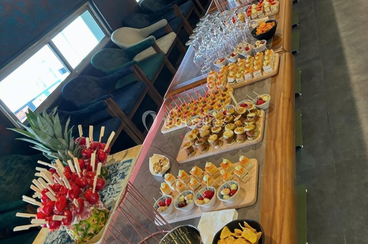 Buffet avec verrines, brochettes de fruits, amuse-bouches et coupes de vin sur une table en bois.