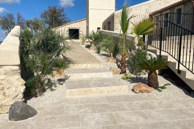 Entrée avec porte vitrée, mur végétal à droite, sol en béton et éclairage au sol.
