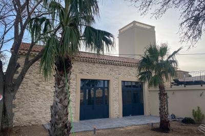 Entrée avec porte vitrée, mur végétal à droite, sol en béton et éclairage au sol.