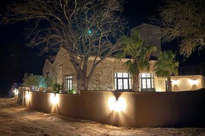 Entrée avec porte vitrée, mur végétal à droite, sol en béton et éclairage au sol.