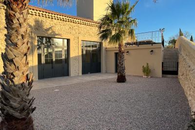 Entrée avec porte vitrée, mur végétal à droite, sol en béton et éclairage au sol.