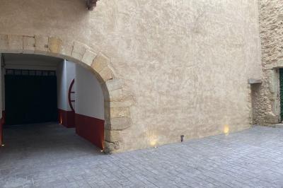 Entrée avec porte vitrée, mur végétal à droite, sol en béton et éclairage au sol.