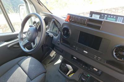 Intérieur d'un véhicule spacieux avec sièges en cuir noir, toit ouvrant et fenêtres équipées de rideaux.