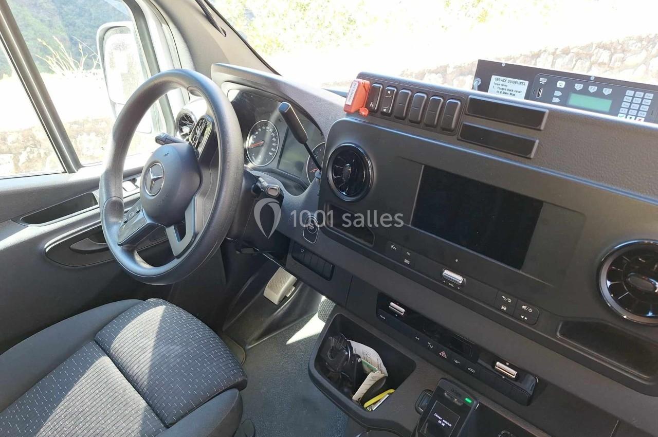 Poste de conduite d'un véhicule utilitaire avec volant, tableau de bord numérique et équipements intégrés.