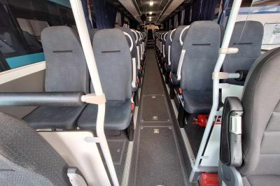 Intérieur d'un véhicule spacieux avec sièges en cuir noir, toit ouvrant et fenêtres équipées de rideaux.