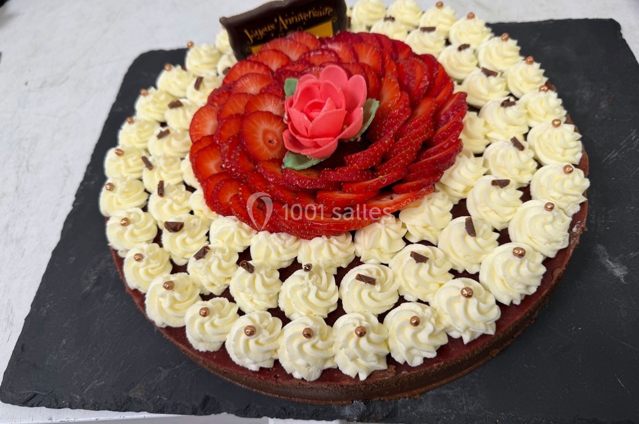 Tarte décorée de fraises tranchées en rosace, crème chantilly et une rose en pâte d'amande au centre.