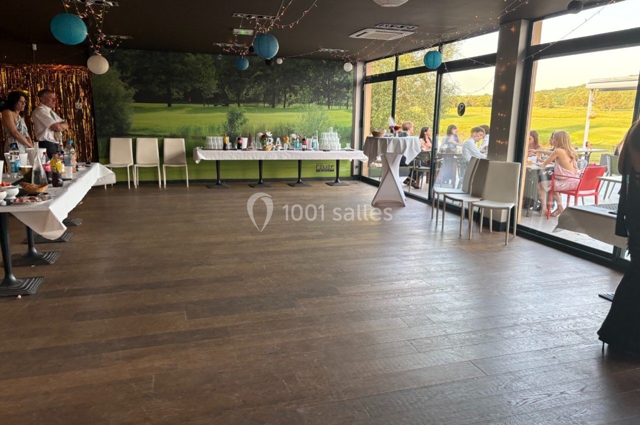 Salle décorée avec des tables dressées et une vue sur une terrasse extérieure donnant sur un paysage verdoyant.