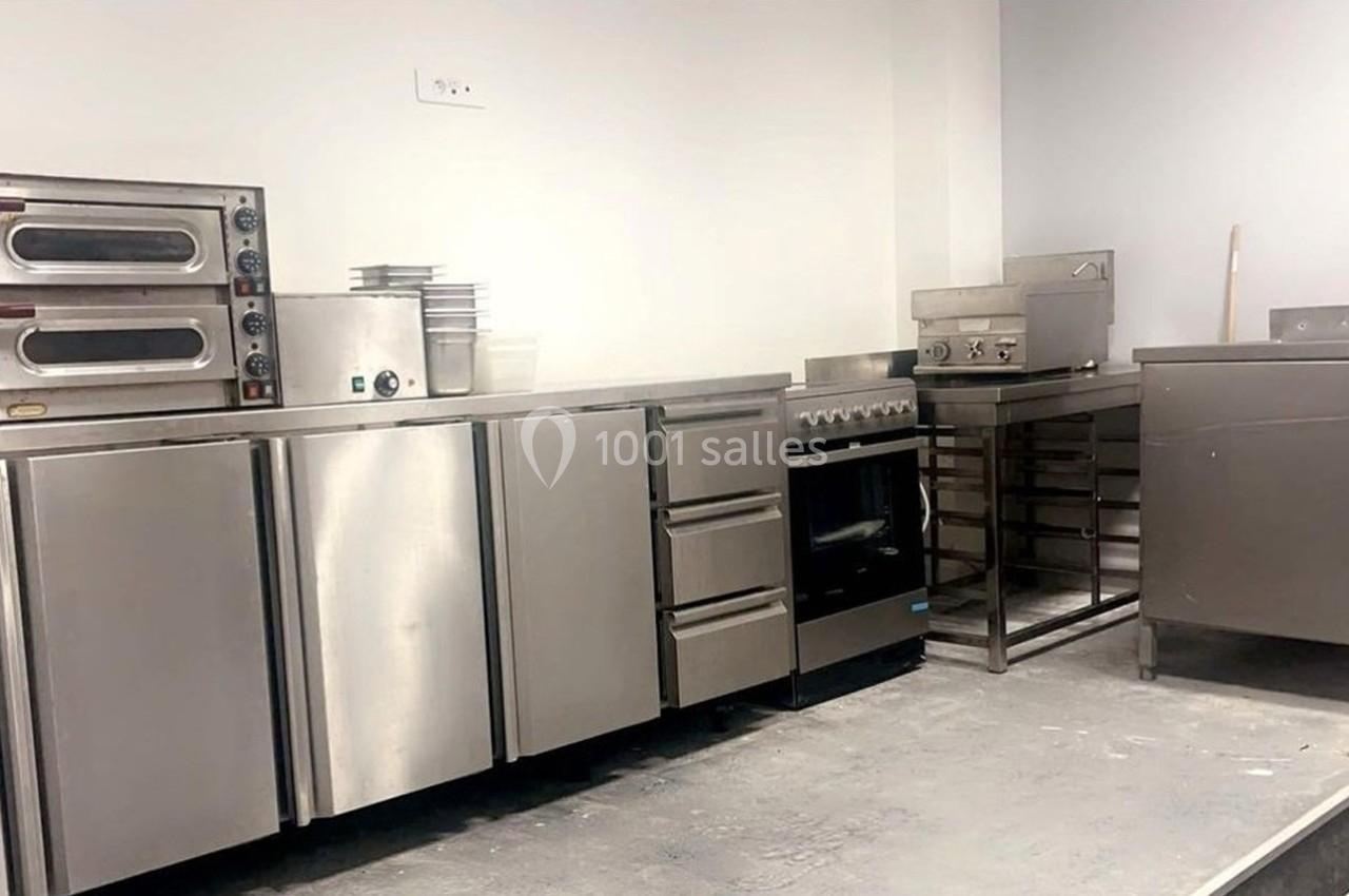 Cuisine professionnelle avec équipements en inox, comprenant fours, plaques de cuisson, plans de travail et rangements.
