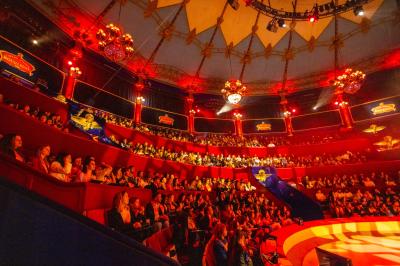 Salle vide avec éclairage rouge, rideaux en arrière-plan, scène surélevée et comptoirs alignés sur les côtés.