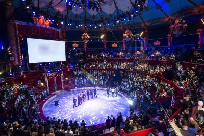 Salle vide avec éclairage rouge, rideaux en arrière-plan, scène surélevée et comptoirs alignés sur les côtés.