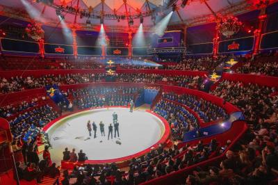 Salle vide avec éclairage rouge, rideaux en arrière-plan, scène surélevée et comptoirs alignés sur les côtés.