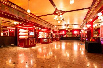 Salle vide avec éclairage rouge, rideaux en arrière-plan, scène surélevée et comptoirs alignés sur les côtés.