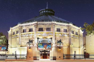 Salle vide avec éclairage rouge, rideaux en arrière-plan, scène surélevée et comptoirs alignés sur les côtés.