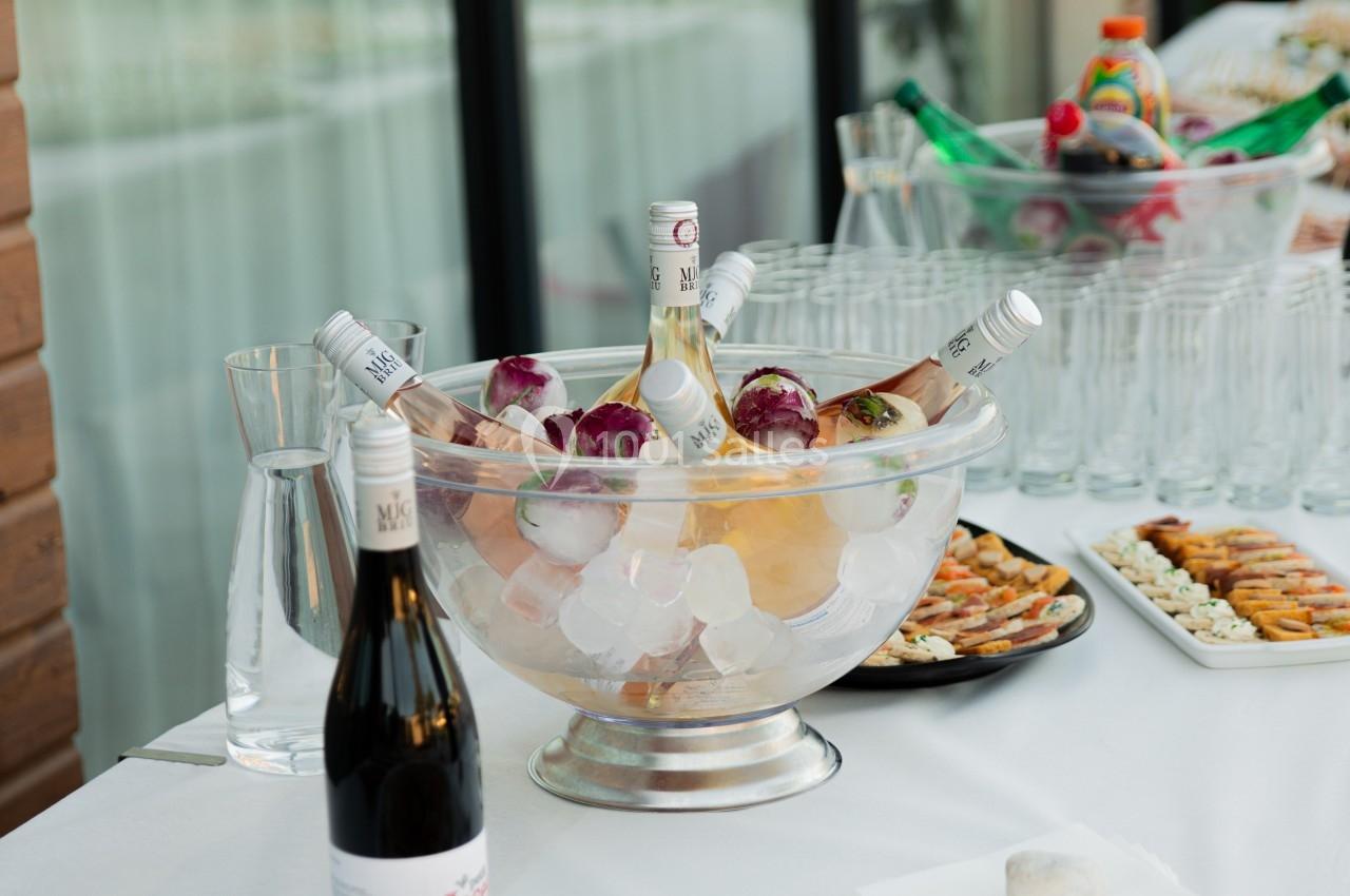 Table dressée avec des amuse-bouches, une coupe de champagne sur glace et des verres alignés en arrière-plan.