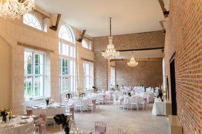 Cour pavée avec un bâtiment en briques rouges et toit en ardoise, entouré de végétation sous un ciel bleu.