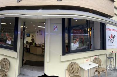 Salle de restaurant lumineuse avec tables et chaises rouges, un client assis et un employé au comptoir.