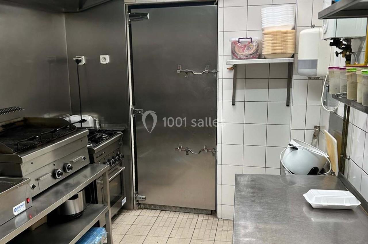 Cuisine professionnelle avec équipements en acier inoxydable, plan de travail, plaques de cuisson et réfrigérateur…