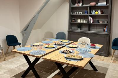 Deux femmes souriantes en tablier, l'une tenant une spatule rouge, l'autre un batteur électrique, dans une cuisine.