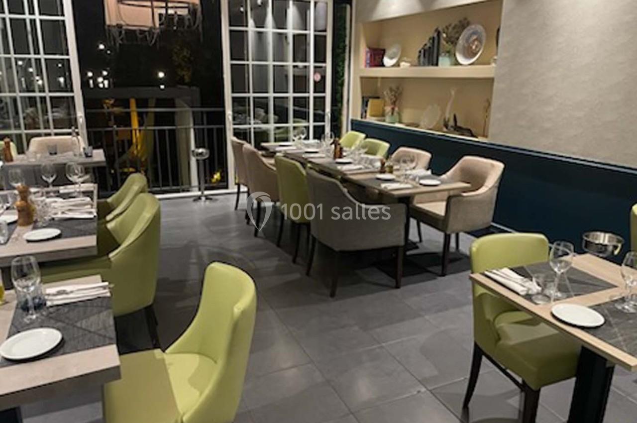 Salle de restaurant moderne avec tables dressées, chaises colorées et grande baie vitrée donnant sur l'extérieur.