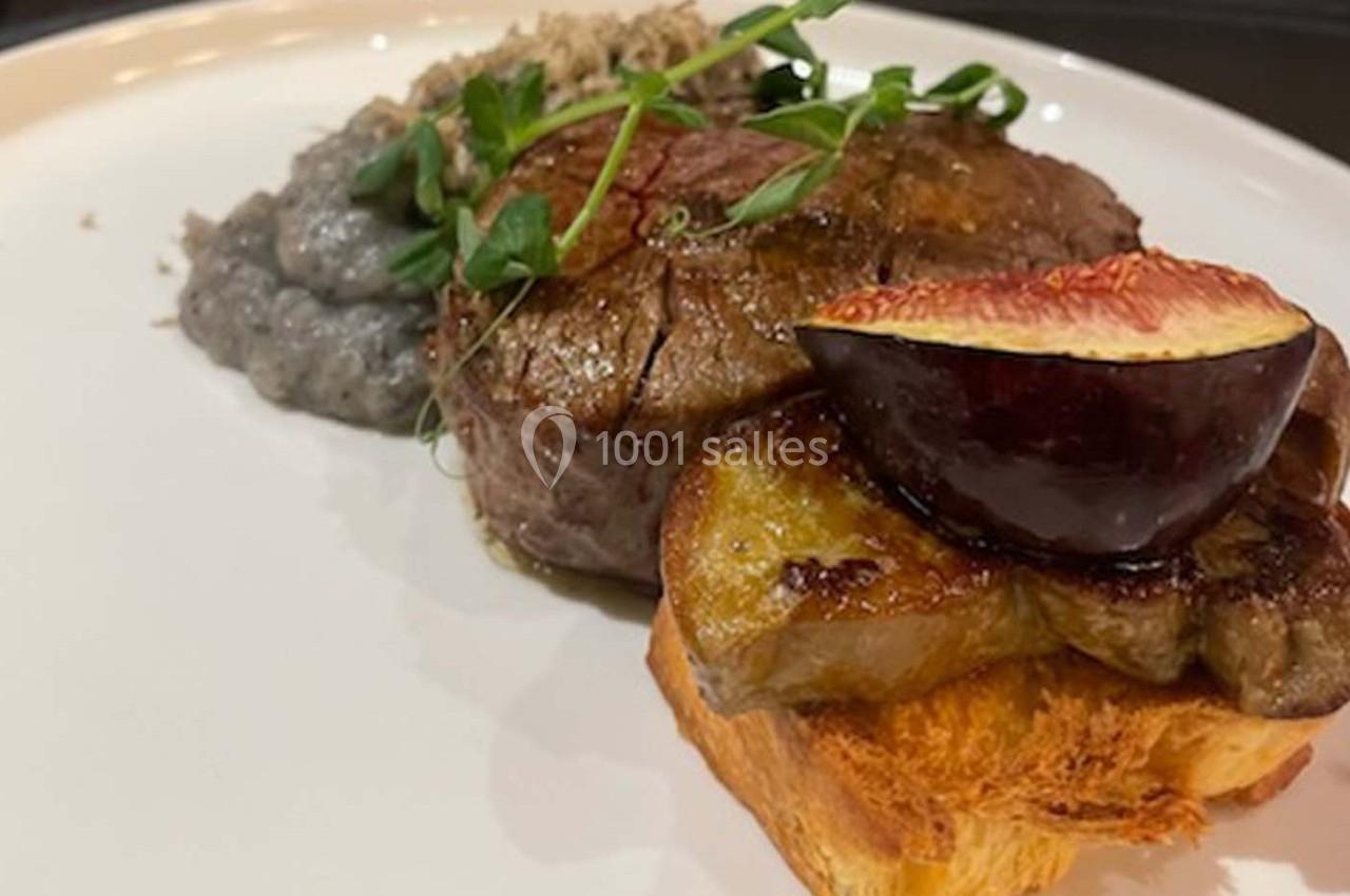 Plat composé d'un filet de viande, d'une tranche de foie gras sur brioche, d'une figue et d'une purée grise, décoré de…