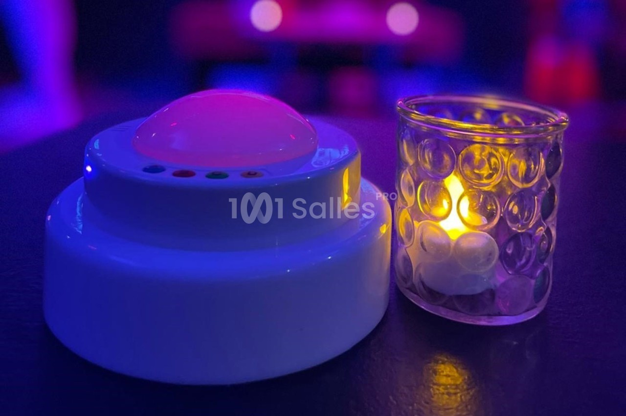 Un bouton lumineux blanc à côté d'une bougie LED dans un environnement faiblement éclairé.