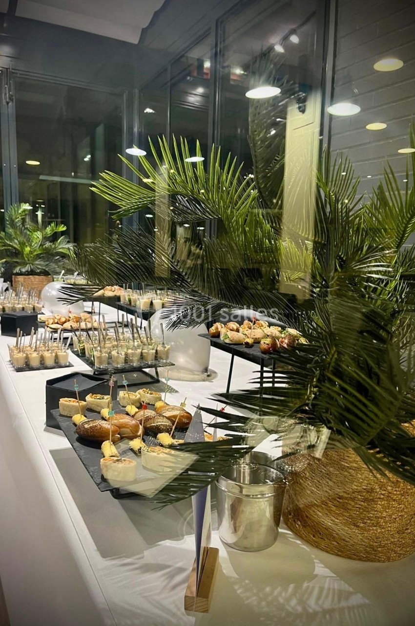 Table de buffet élégante avec desserts variés, plantes décoratives et éclairage intérieur moderne en arrière-plan.