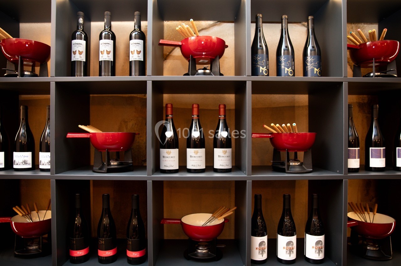 Étagères avec bouteilles de vin et sets à fondue rouges et blancs, disposés de manière ordonnée.