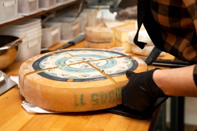 Miniature Morbier Fondue au fromage dans un caquelon rouge avec des morceaux de pain trempés, accompagnée de vin et de cornichons.