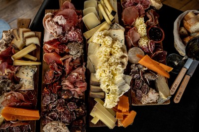 Miniature Planche Fondue au fromage dans un caquelon rouge avec des morceaux de pain trempés, accompagnée de vin et de cornichons.