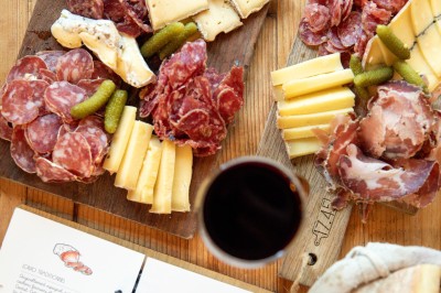 Miniature Planche Fondue au fromage dans un caquelon rouge avec des morceaux de pain trempés, accompagnée de vin et de cornichons.
