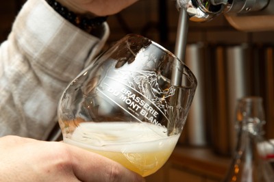 Fondue au fromage dans un caquelon rouge, avec du pain trempé sur des fourchettes, accompagnée de vin et de cornichons.