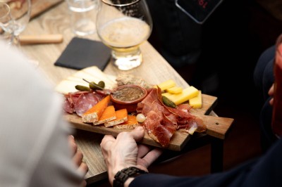 Fondue au fromage dans un caquelon rouge, avec du pain trempé sur des fourchettes, accompagnée de vin et de cornichons.