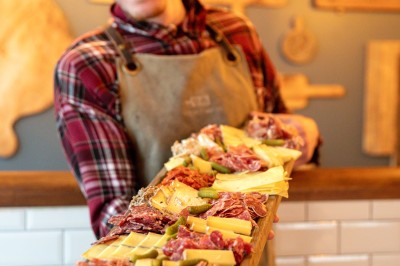 Fondue au fromage dans un caquelon rouge, avec du pain trempé sur des fourchettes, accompagnée de vin et de cornichons.