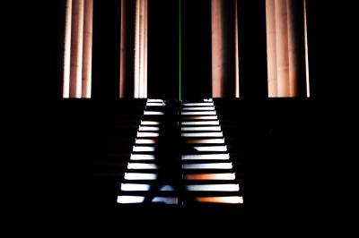 Voiture sportive bleue stationnée sur une place pavée devant un monument en bronze et des bâtiments historiques.