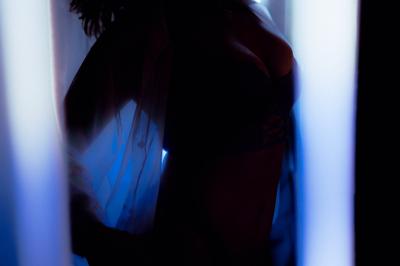 Voiture sportive bleue stationnée sur une place pavée devant un monument en bronze et des bâtiments historiques.